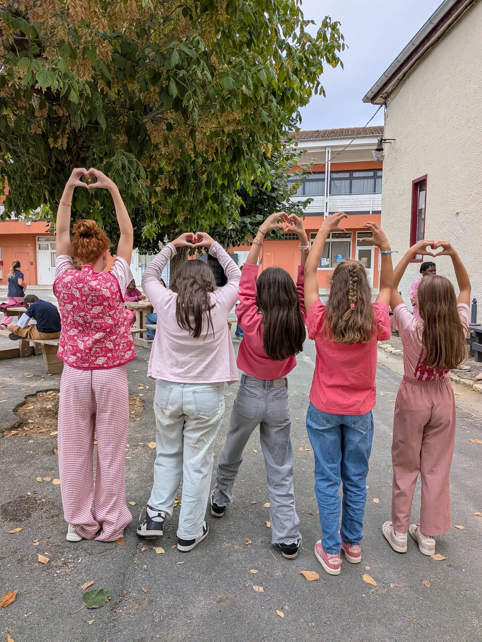Élèves en rose faisant des cœurs avec leurs mains