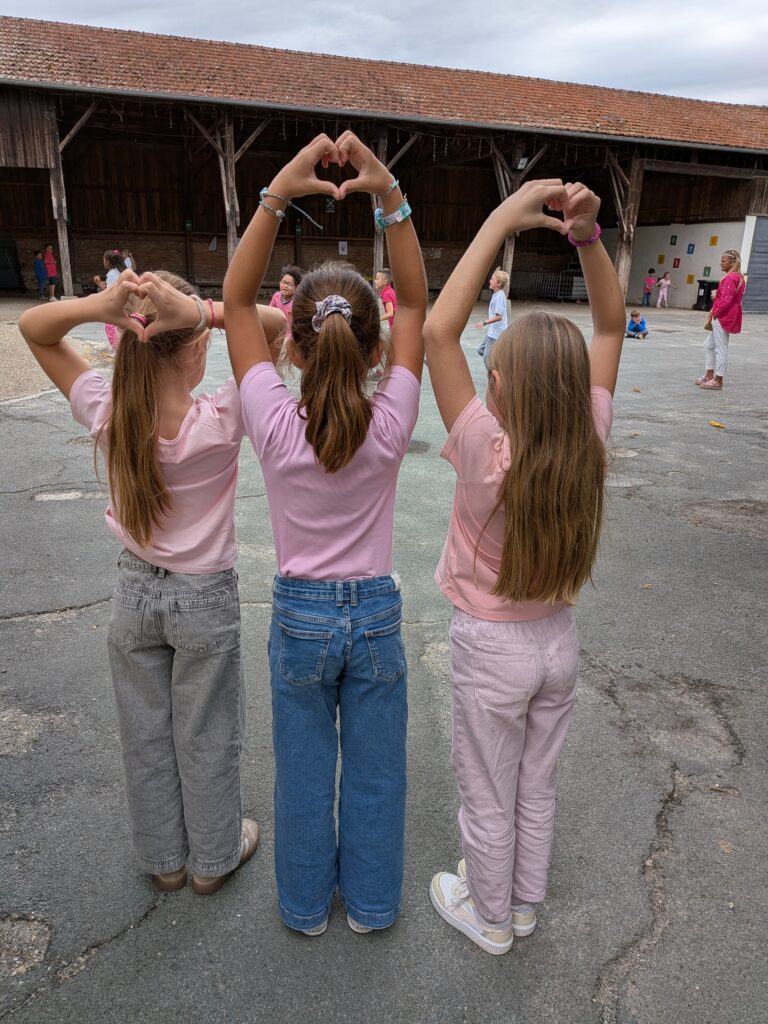 Élèves en rose formant des cœurs avec leurs mains