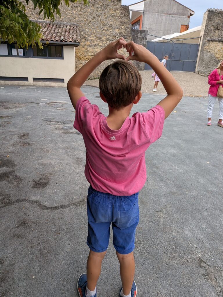 Un élève en rose fait un cœur avec ses bras
